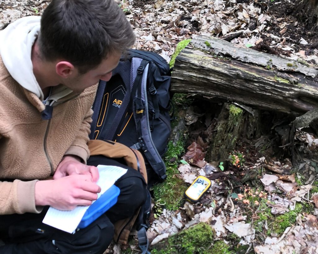 Tim Noah Fischer bei der Geländearbeit im Wald – Notizen zur Schleimpilz‑Kartierung.